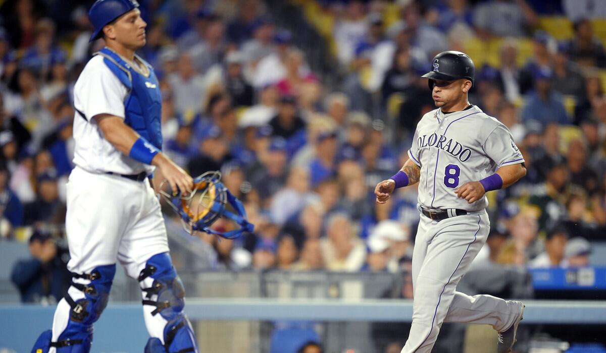 The Colorado Rockies' Bob Geren, right, scores on a single by Daniel Descalso as Dodgers catcher A.J. Ellis stands at the plate during the seventh inning on June 8.