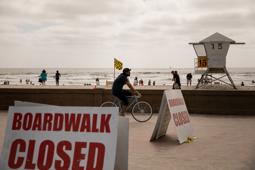 A bicyclist rides along the boardwalk in Mission Beach on Friday, ahead of Memorial Day weekend. The boardwalk is supposed to be closed to pedestrians except to cross over it on the way to and from the sand.