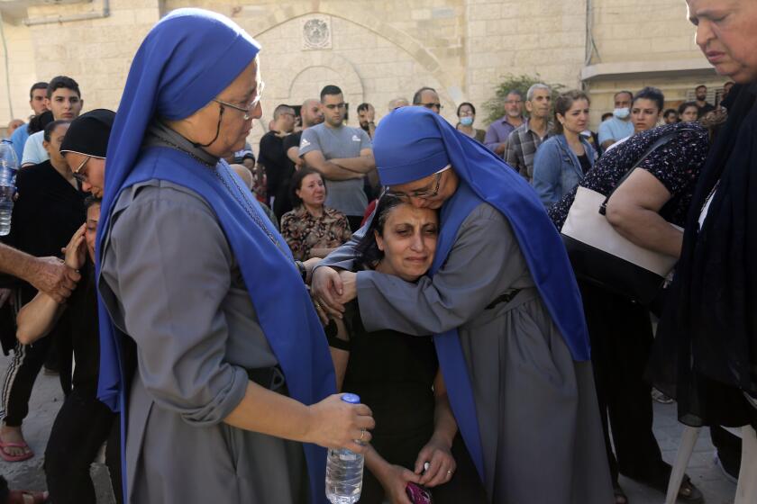 Nuns comfort a Palestinian woman as she mourns the death of a relative, killed in Israeli airstrikes that hit a church, during a funeral service in Gaza City, Friday, Oct. 20, 2023. An Israeli airstrike hit a Greek Orthodox church housing displaced Palestinians near the hospital late Thursday. The military said it had targeted a Hamas command center nearby, causing damage to a church wall. Gaza’s Hamas-run Health Ministry said 16 Palestinian Christians were killed. (AP Photo/Abed Khaled)