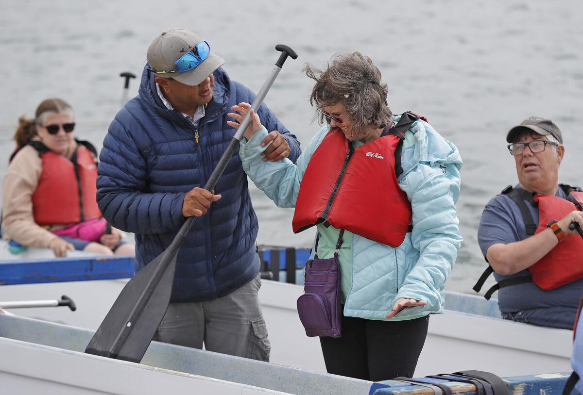 RJ De Rama, left, with client Gina Giglio as they head out for an outrigger session at the Newport Aquatics Center Thursday. 