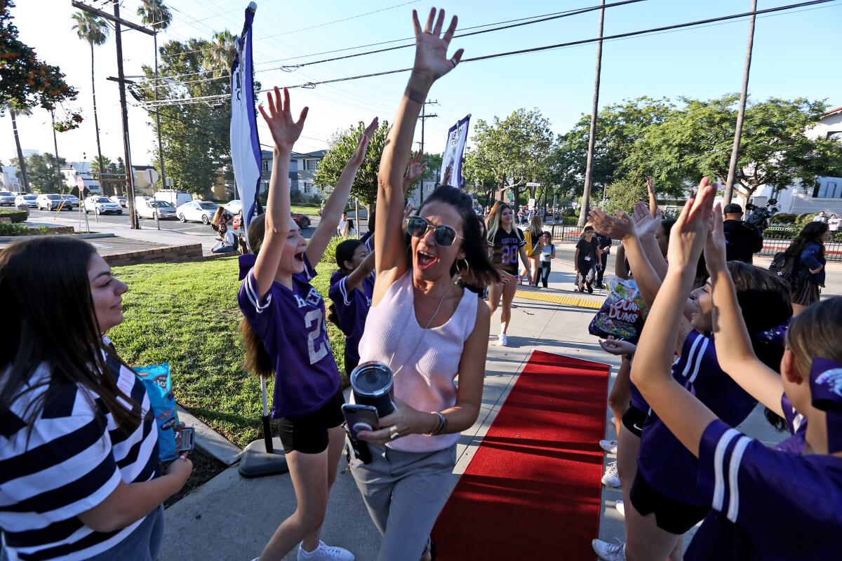 Hoover High School principal Jennifer Earl gets high-fives from a line of cheerleaders on the first day of school for Glendale Unified School District on Wednesday.
