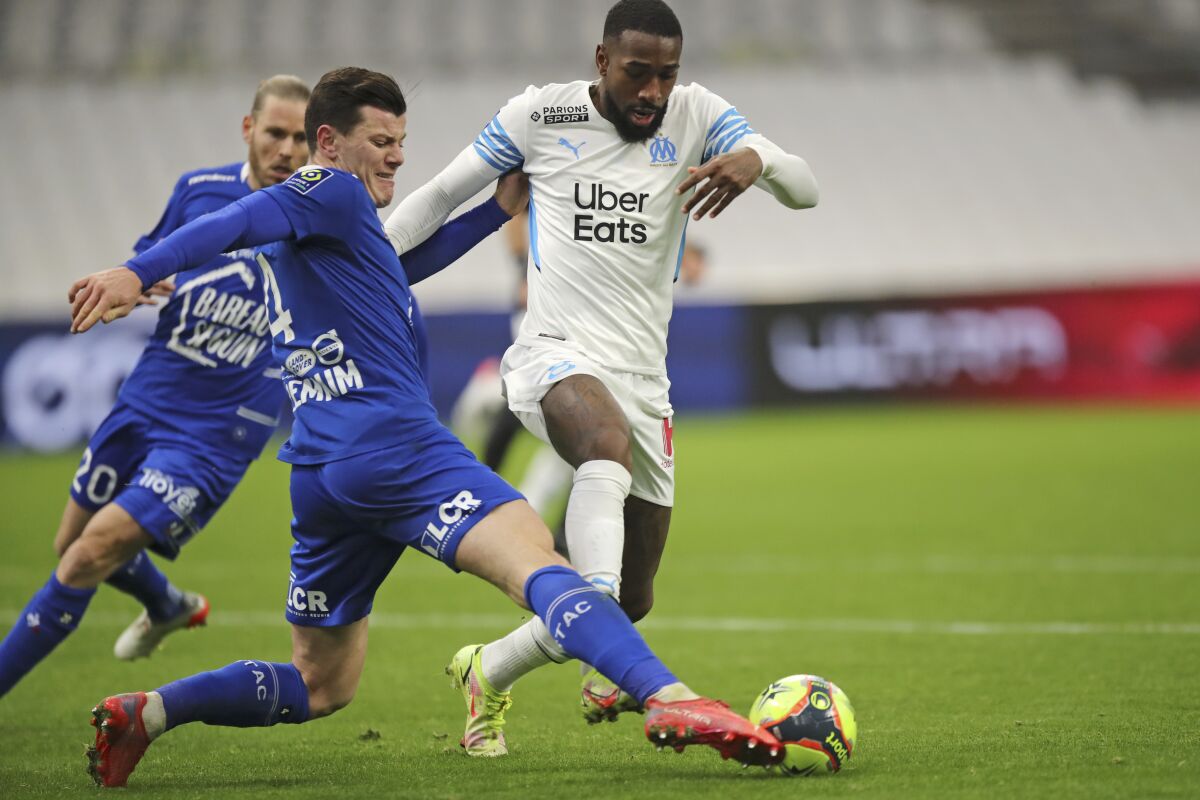 Troyes' Giulian Biancone, left, challenges Marseille's Gerson during the French League One soccer match between Marseille and Troyes at the Veldrome stadium in Marseille, France, Sunday, Nov. 28, 2021. (AP Photo/Daniel Cole)