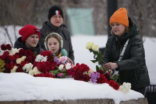 A woman lays flowers to pay the last respect to Alexei Navalny at the monument, a large boulder from the Solovetsky islands, where the first camp of the Gulag political prison system was established, near the historical the Federal Security Service (FSB, Soviet KGB successor) building in Moscow, Russia, on Sunday, Feb. 18, 2024. Russians across the vast country streamed to ad-hoc memorials with flowers and candles to pay tribute to Alexei Navalny, the most famous Russian opposition leader and the Kremlin's fiercest critic. Russian officials reported that Navalny, 47, died in prison on Friday. (AP Photo/Alexander Zemlianichenko)