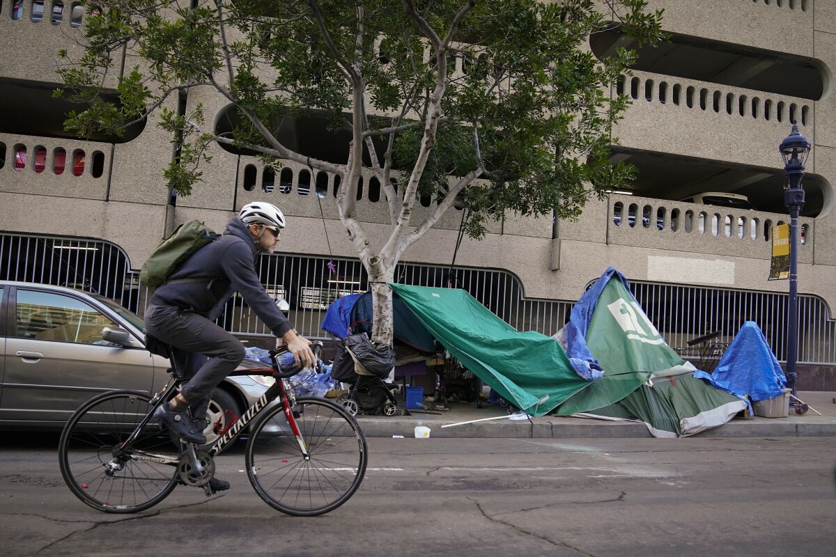 A photo from January 2023 shows a bicycle passing homeless encampments in downtown San Diego.
