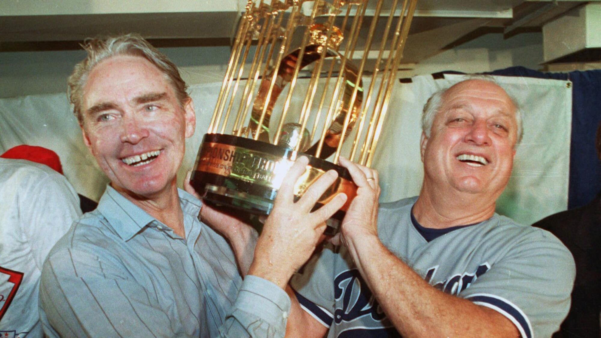 Dodgers manager Tommy Lasorda, right, and team vice president Fred Claire and lift the 1988 championship trophy.