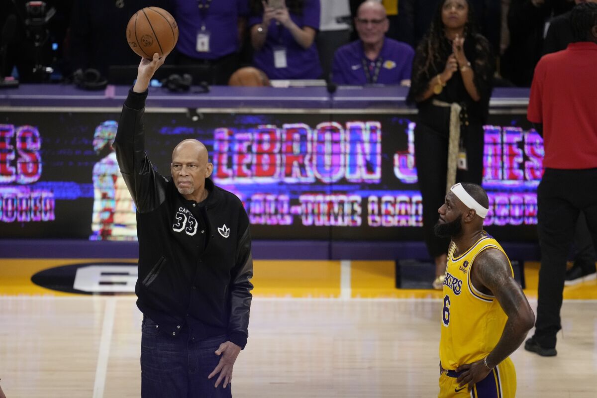 Kareem Abdul-Jabbar, left, holds up the ball before handing it to Los Angeles Lakers forward LeBron James after James passed Abdul-Jabbar to become the NBA's all-time leading scorer during the second half of an NBA basketball game against the Oklahoma City Thunder Tuesday, Feb. 7, 2023, in Los Angeles. (AP Photo/Marcio Jose Sanchez)