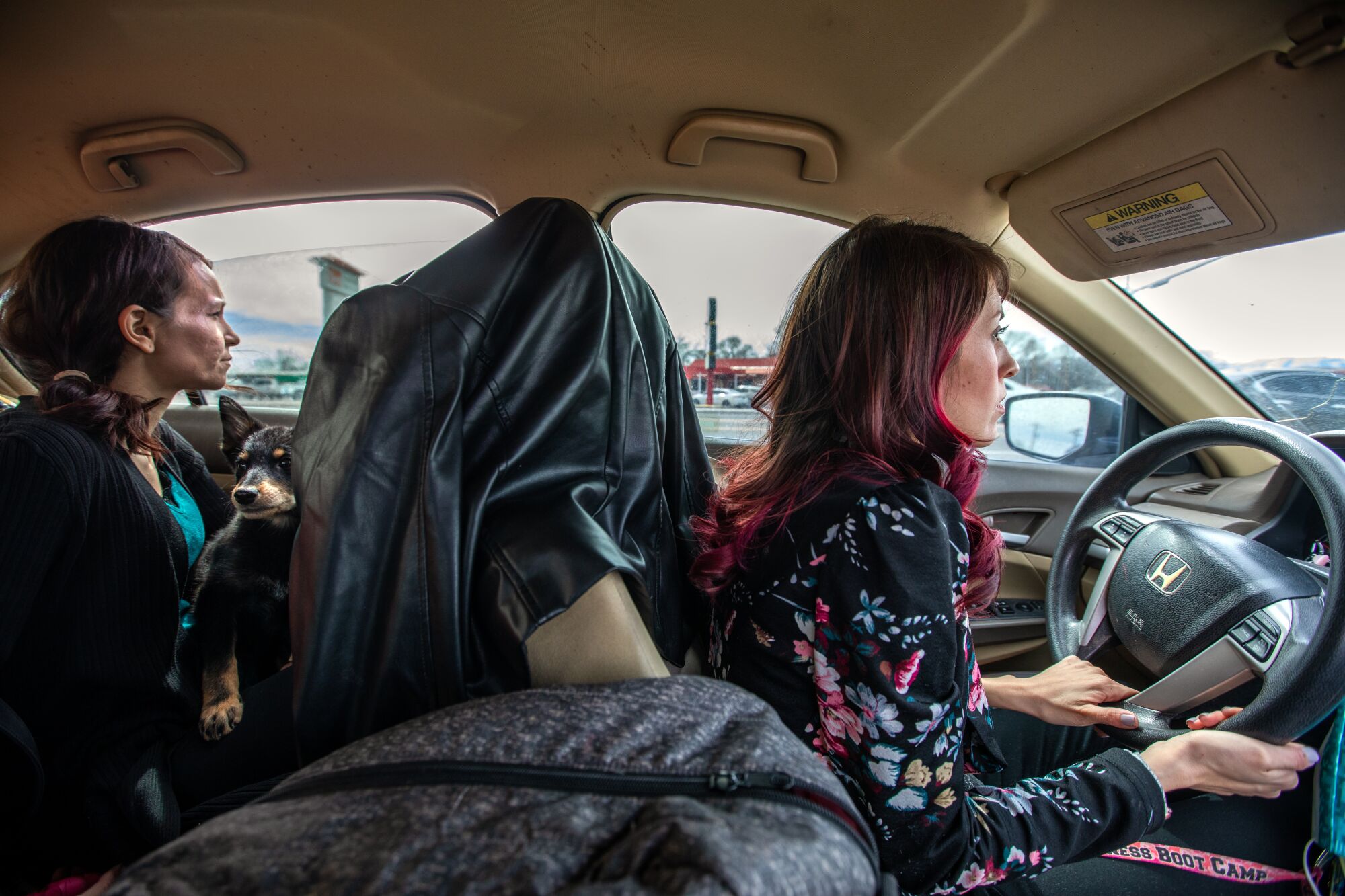 Kobieta siedzi na tylnym siedzeniu, gdy inna kobieta prowadzi