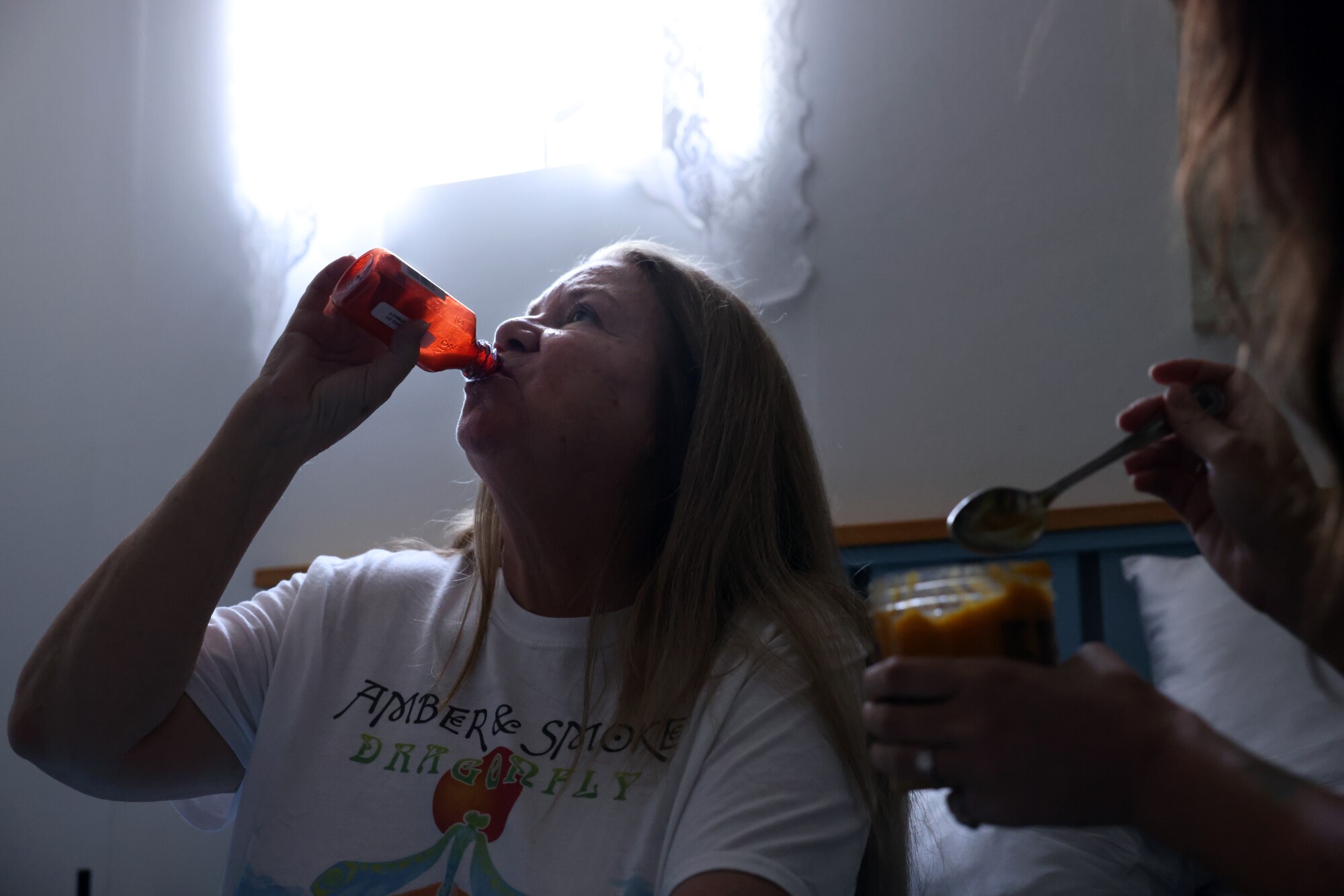 A woman drinks from a medication bottle