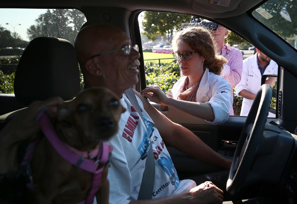 Touro Medical School student Caitlin Harris administers a flu vaccine to a person in a car during a drive-thru flu shot clinic at Doctors Medical Center in San Pablo, Calif. last year.