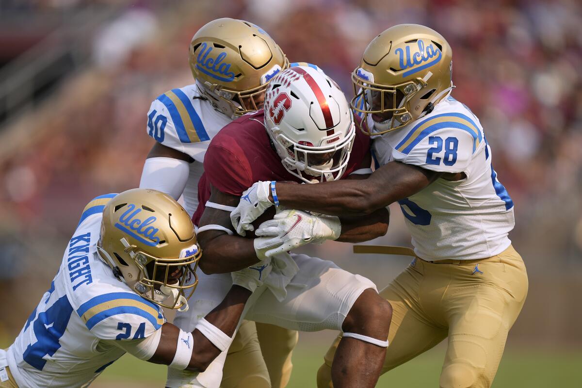 Stanford running back Nathaniel Peat is stopped by UCLA defenders.