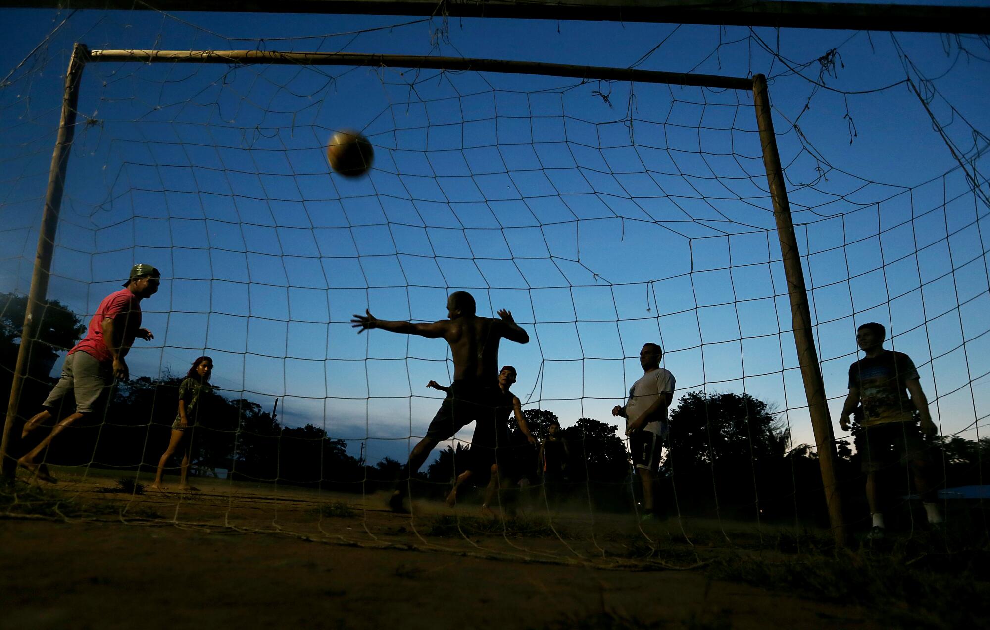 Residents of Tumbira, Brazil, play soccer as the sun sets