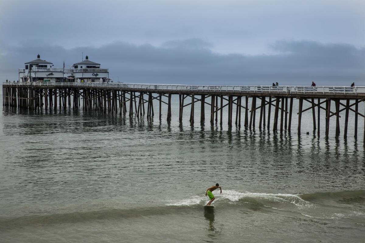 Christian Rodriguez, 19, of Santa Barbara skimboards Thursday at the Malibu Pier with low clouds in the background.