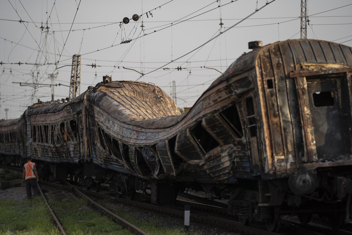 A railway worker stands next to a heavily damaged train after a Russian attack.