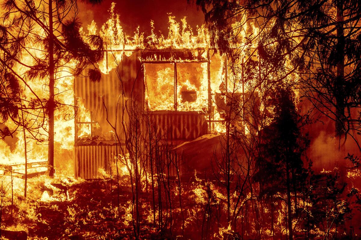 Flames from the Dixie fire consume a home on Highway 89 in Greenville, Calif.