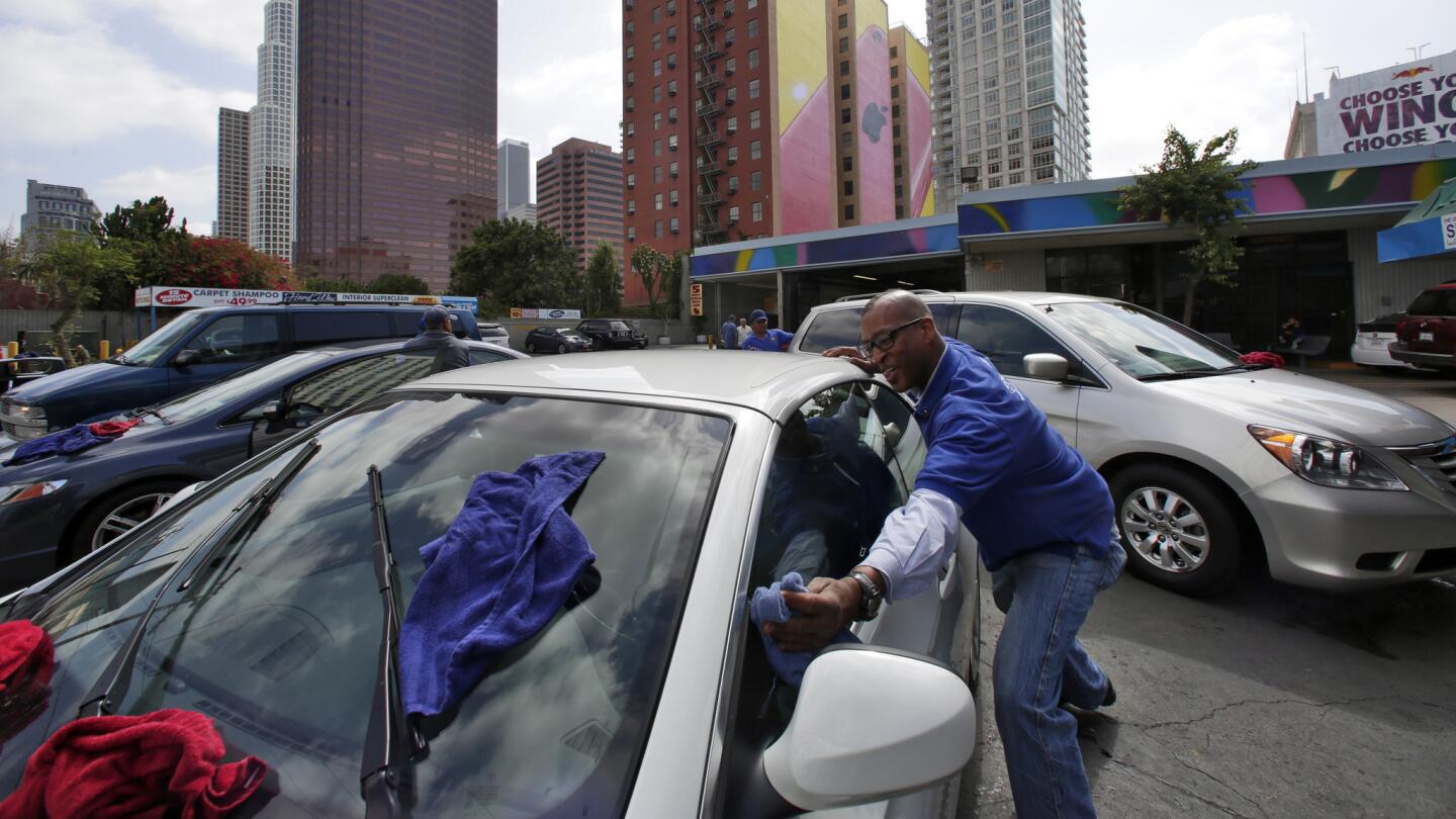 Robert O'Quinn works on a car at Downtown Car Wash at Olympic Boulevard and Figueroa Street. It was bought by a developer who plans to build a high-rise hotel-and-residential complex