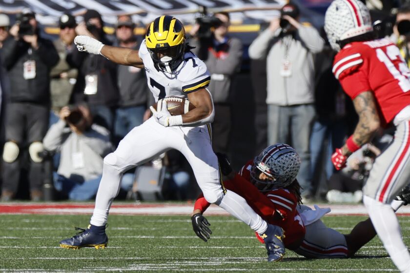 Ohio State defensive back Ronnie Hickman, right, tries to tackle Michigan running back Donovan Edwards during the first half of an NCAA college football game on Saturday, Nov. 26, 2022, in Columbus, Ohio. (AP Photo/Jay LaPrete)
