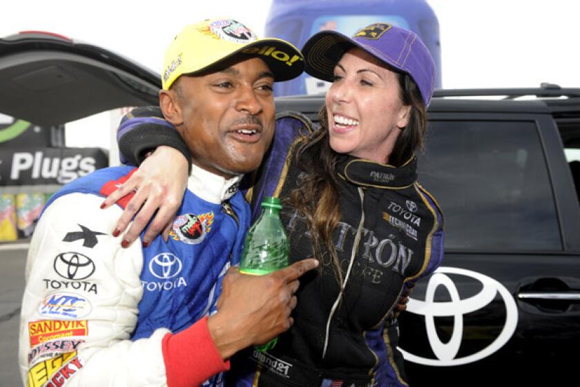 Drag racer Antron Brown, who took the top fuel class, celebrates with Alexis DeJoria after she won her first NHRA funny car title on Sunday.