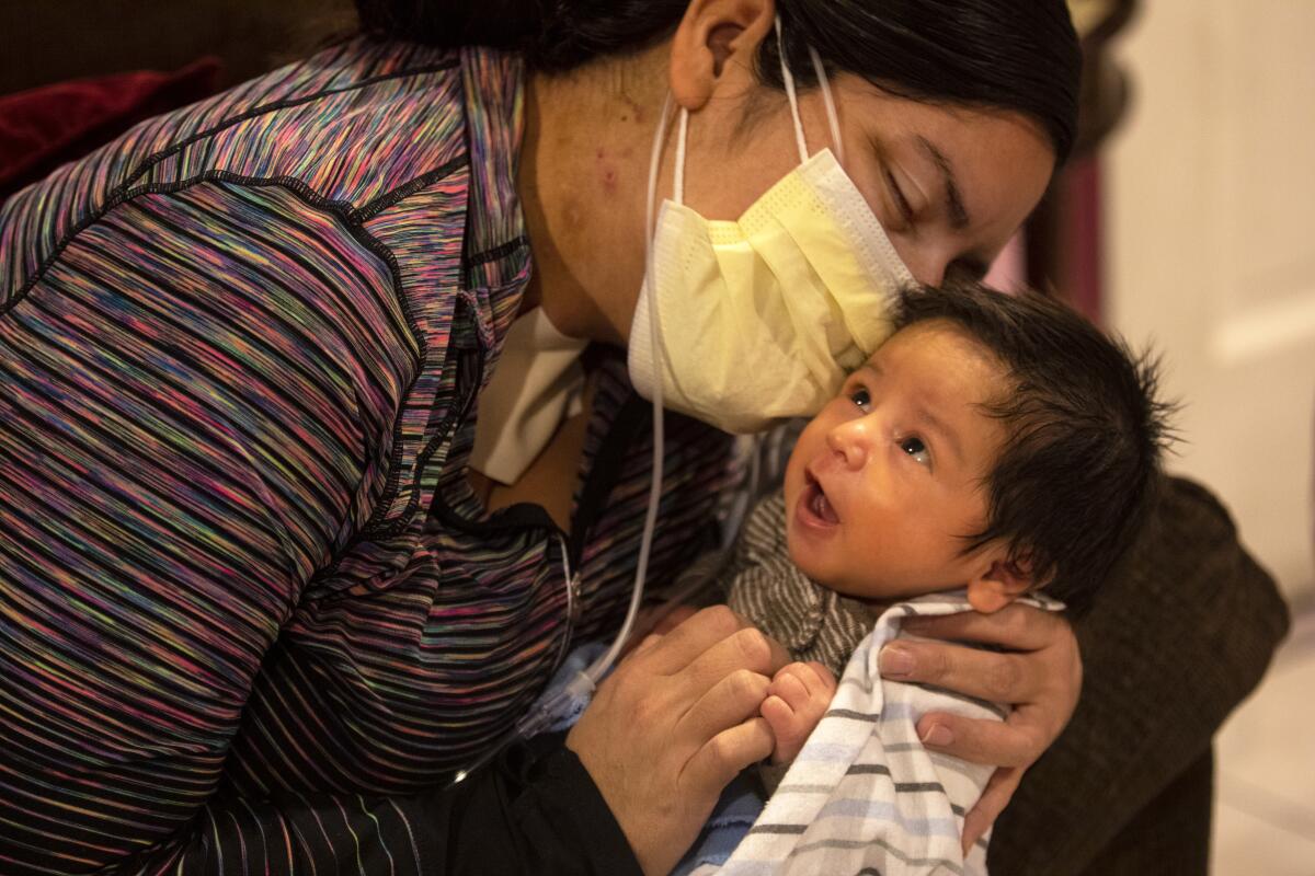 A woman in a mask holds her newborn son