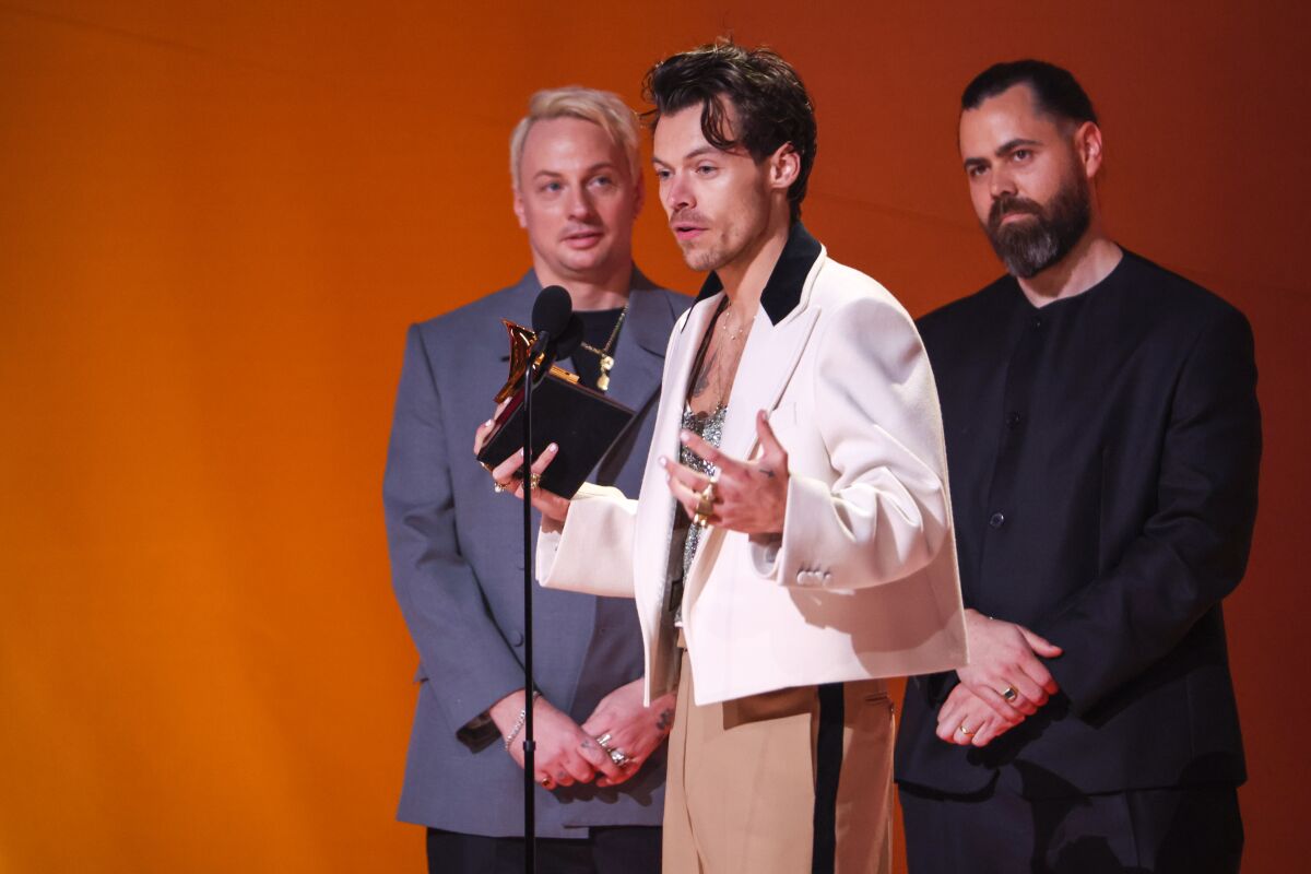 A guy in white jacket accepts a Grammy award