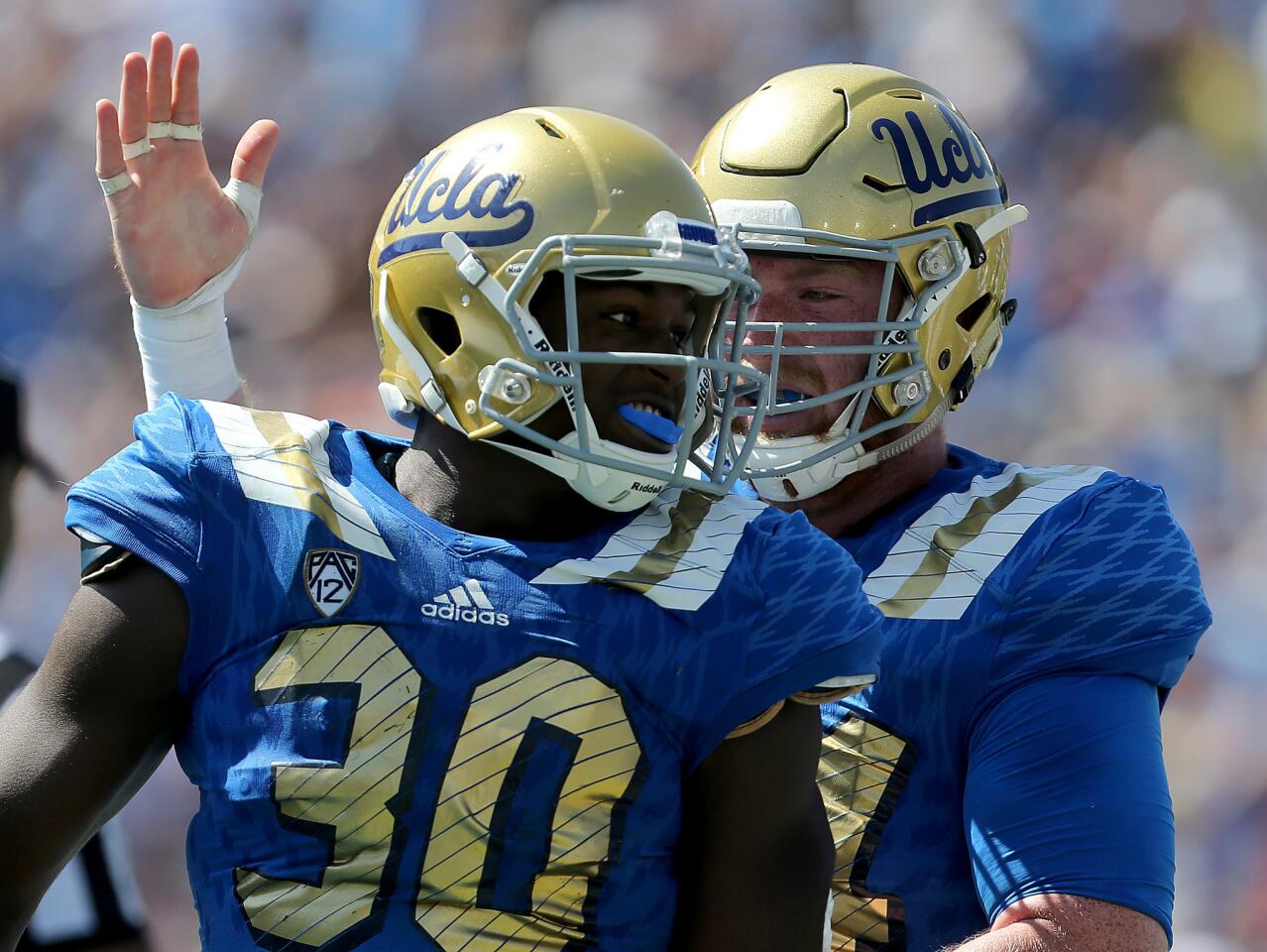 UCLA linebacker Myles Jack is congratulated by center Jake Brendel after scoring a touchdown against Virginia. Both will be in Indianapolis for the NFL Scouting Combine.
