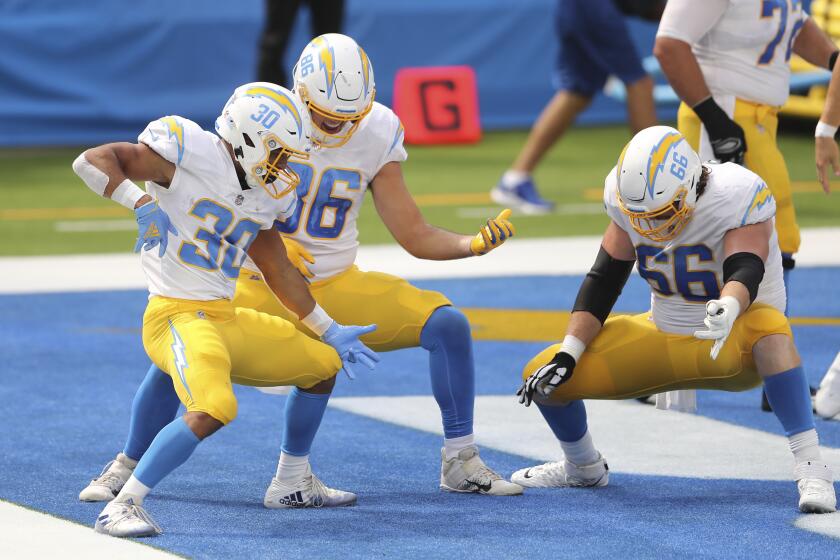 Los Angeles Chargers running back Austin Ekeler (30) follows his touchdown with a ai guitar celebration with Los Angeles Chargers tight end Hunter Henry (86) and Los Angeles Chargers center Dan Feeney (66) during an NFL football game against the Carolina Panthers, Sunday, Sept. 27, 2020, in Inglewood, Calif. (AP Photo/Peter Joneleit)