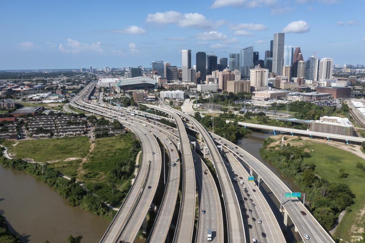 An aerial view of freeway lanes crossing a bayou looking toward downtown Houston