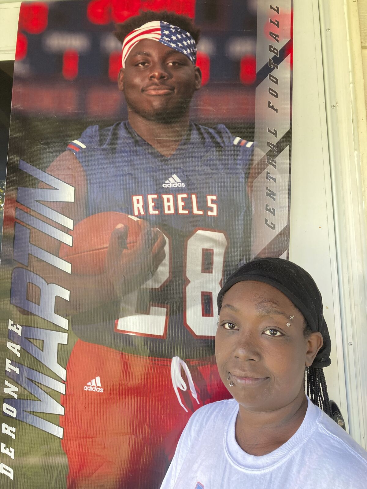 Ericka Lotts stands next to a poster of her son, Derontae Martin, from his high school football playing days, on Friday, Sept. 17, 2021, at her home in Ferguson, Mo. Lotts is frustrated by the pace of the investigation into Martin's death. The 19-year-old died in April at a home in rural Missouri. (AP Photo by Jim Salter)
