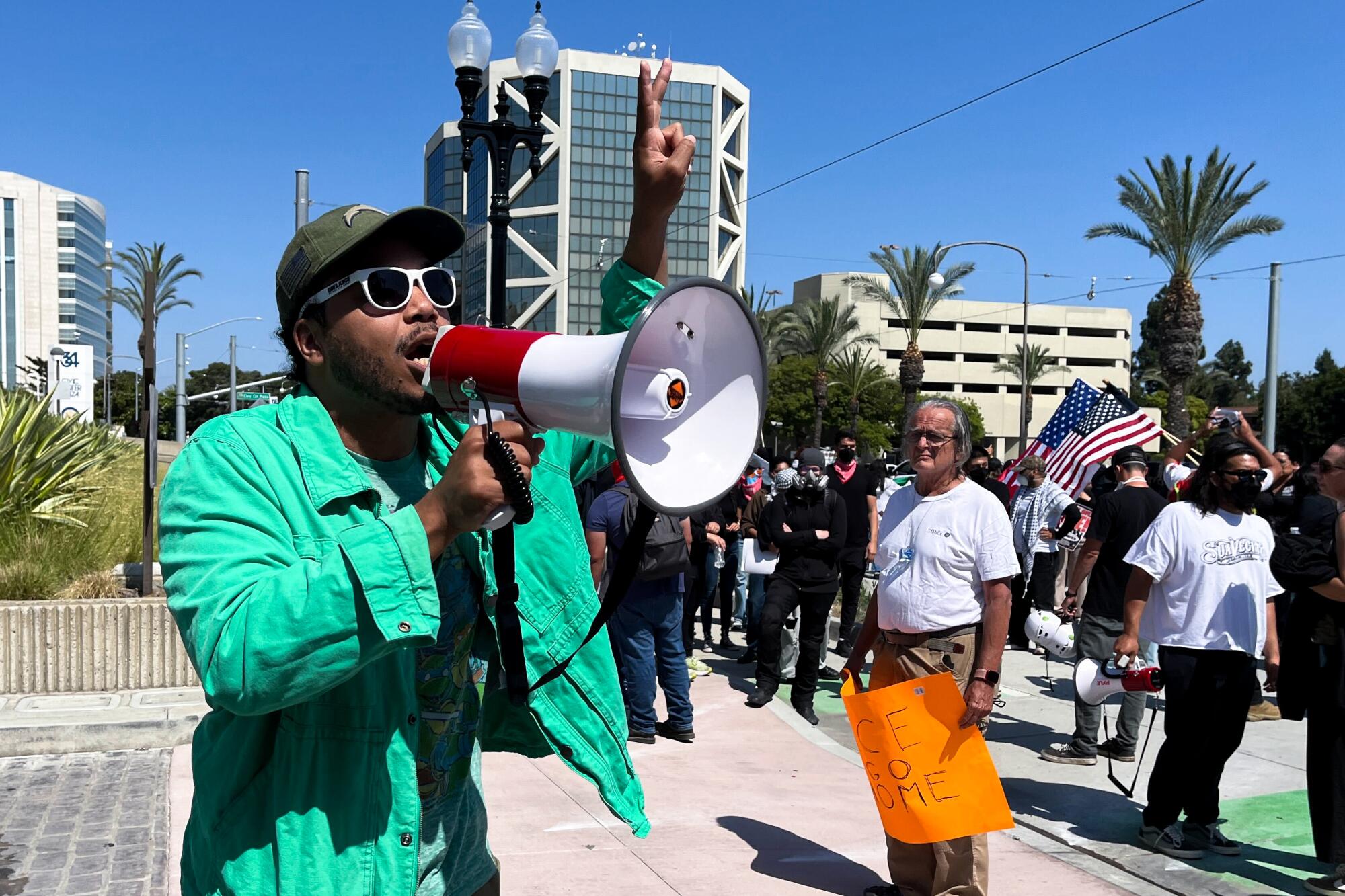 A man in a bright green jacket speaks into a bullhorn.