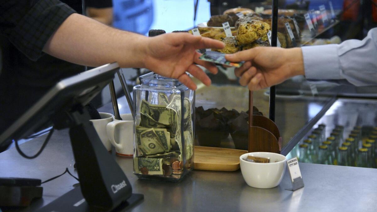 A customer hands a credit card to a cashier at a coffee shop.