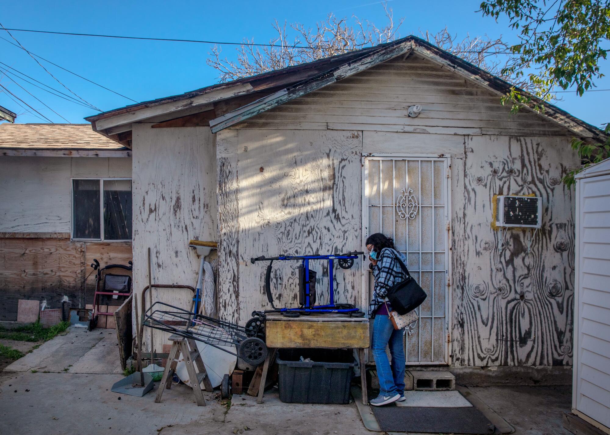 Maria Diaz knocks at the door of a backyard home