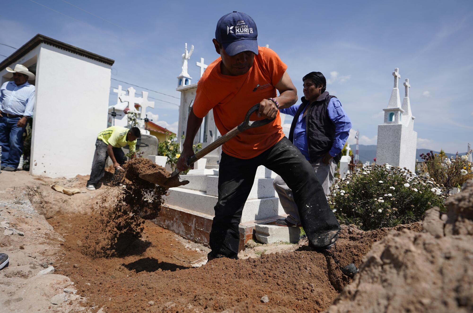 Un trabajador palea arena sobre la tumba de María Eugenia Chávez Segovia en el cementerio de Tultepec.