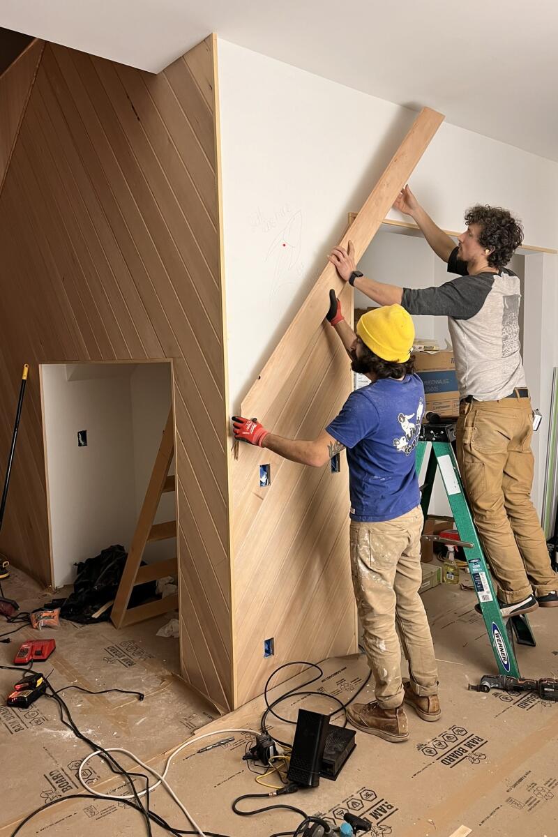 Daniel Sheron and a friend install Western Hemlock boards on the wall of the kitchen.