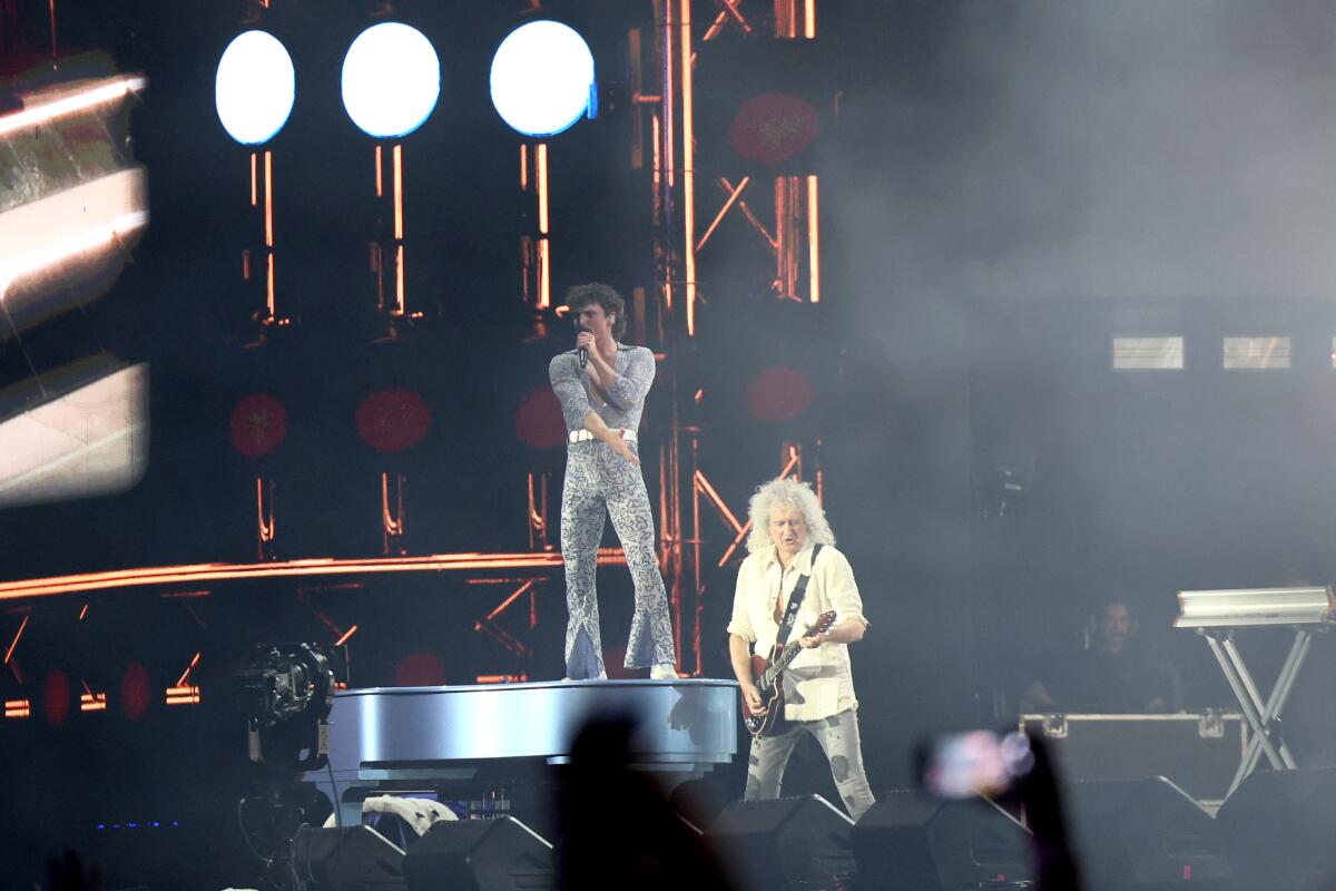 Benson Boone stands connected a soft adjacent to Queen guitarist Brian May