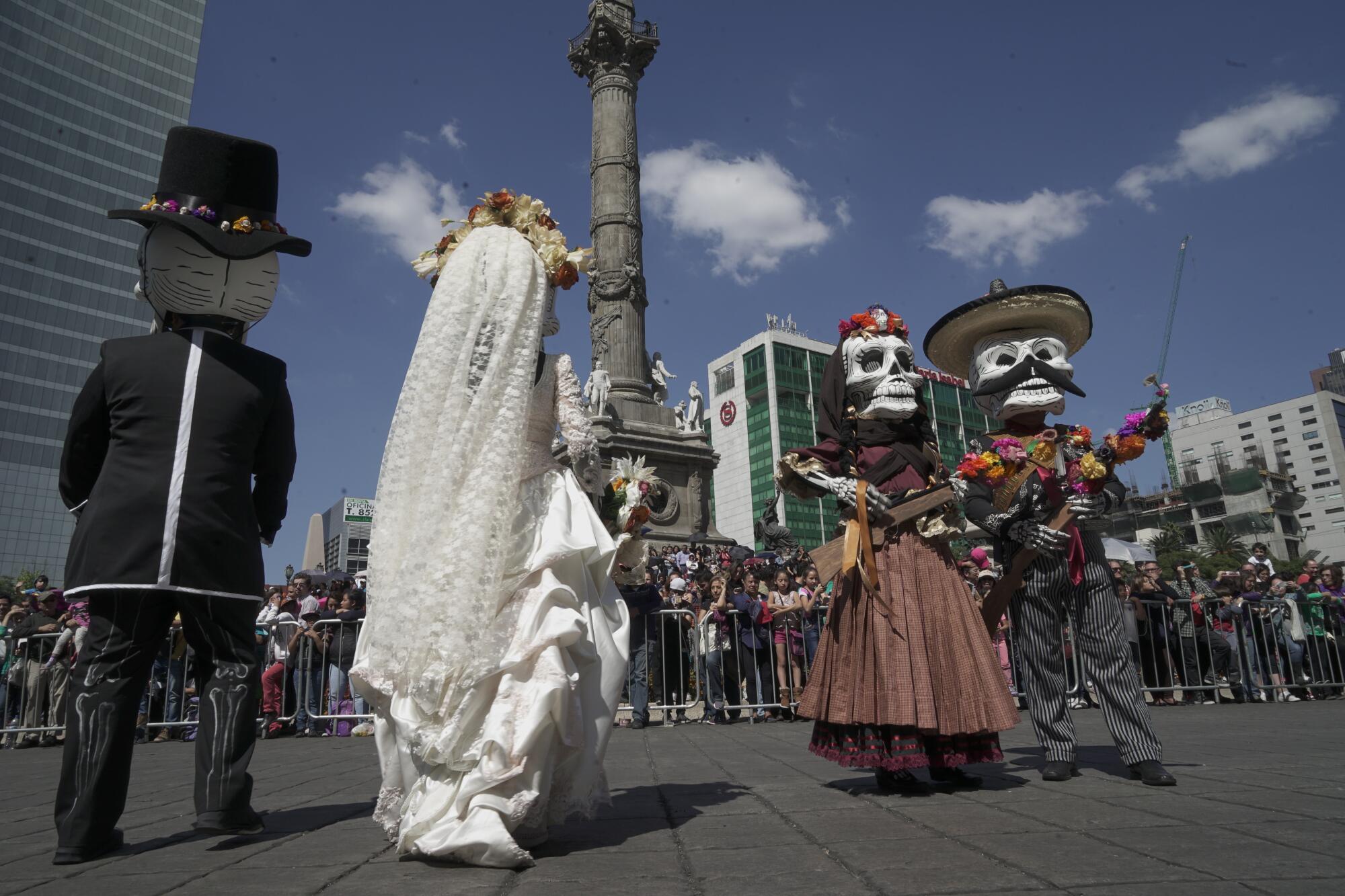 Two couples dressed in skeletal costumes dance in the street