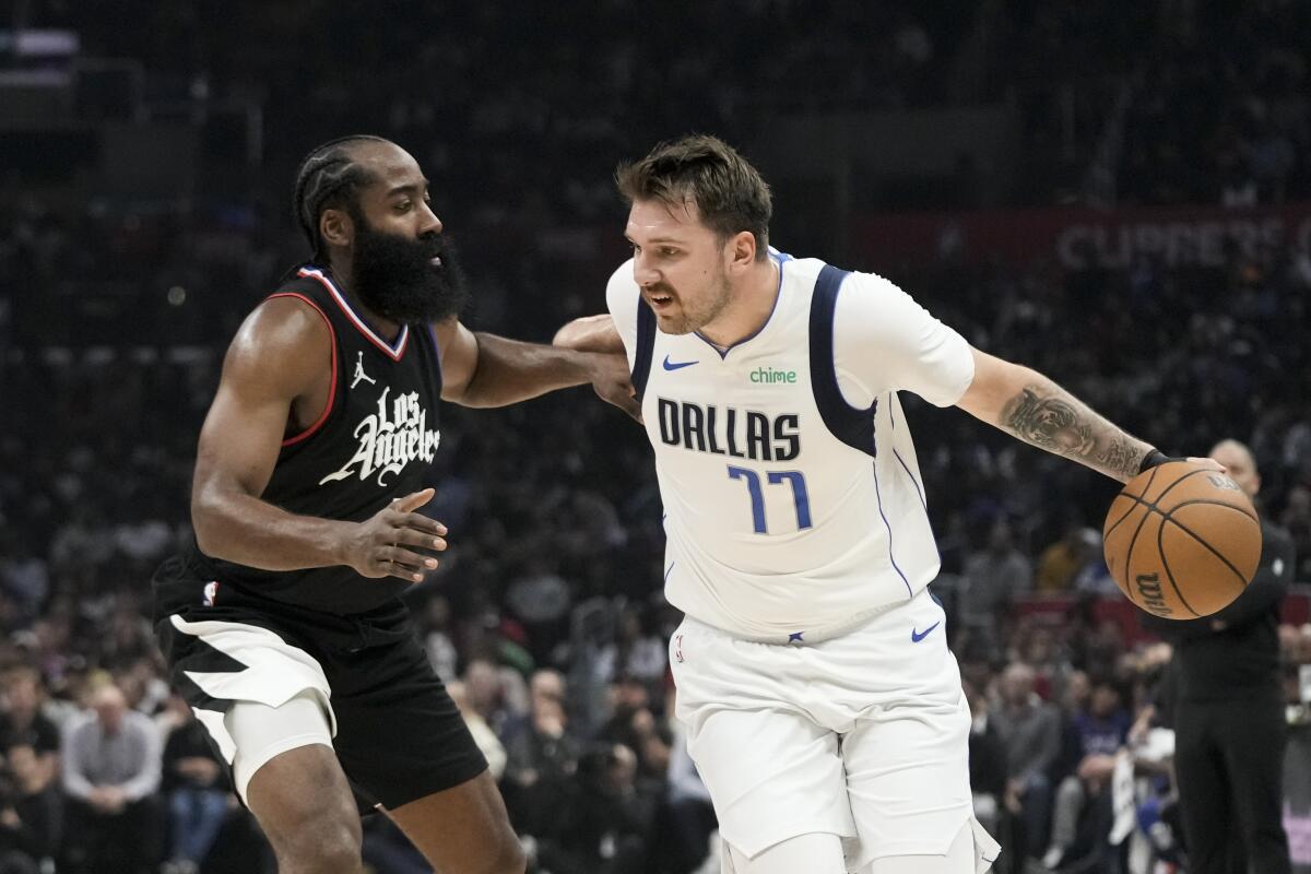 James Harden pressures Luka Doncic, who is dribbling the ball.