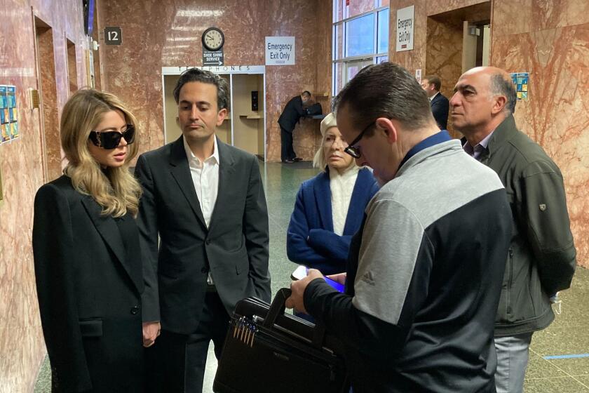 Khazar Elyassnia, left, stands in the Hall of Justice in San Francisco on Friday, April 14, 2023, ahead of an appearance by her brother, Nima Momeni, who has been charged with murder in the death of tech entrepreneur Bob Lee. Elyassnia's husband, Dino Elyssania, is to her right. Momeni's arraignment was rescheduled to April 25, 2023, and he did not enter a plea. (AP Photo/Olga R. Rodriguez)