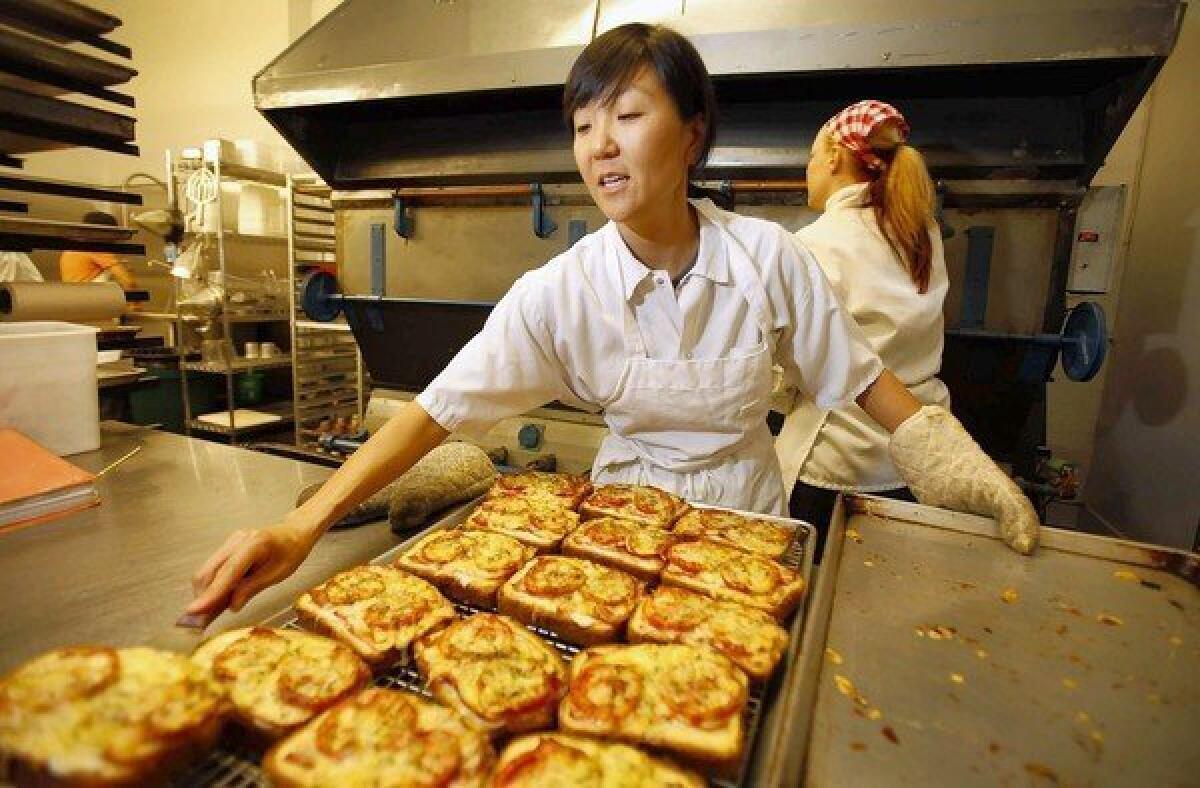 Na Young Ma, chef and owner of Proof Bakery, pulls some savory pastries from the giant oven.