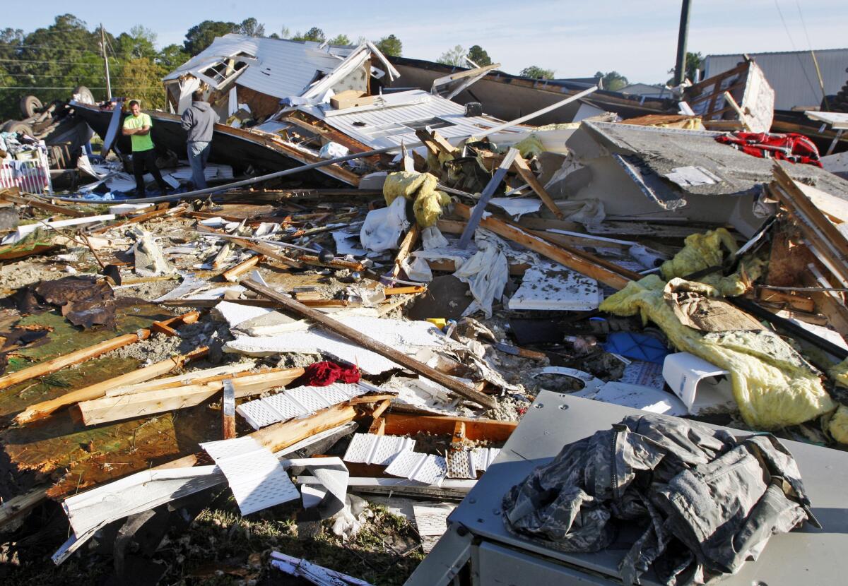 People stand among the remains of a mobile home Saturday that was destroyed when a tornado touched down along Black Jack-Simpson Road in Greenville, N.C., on Friday.