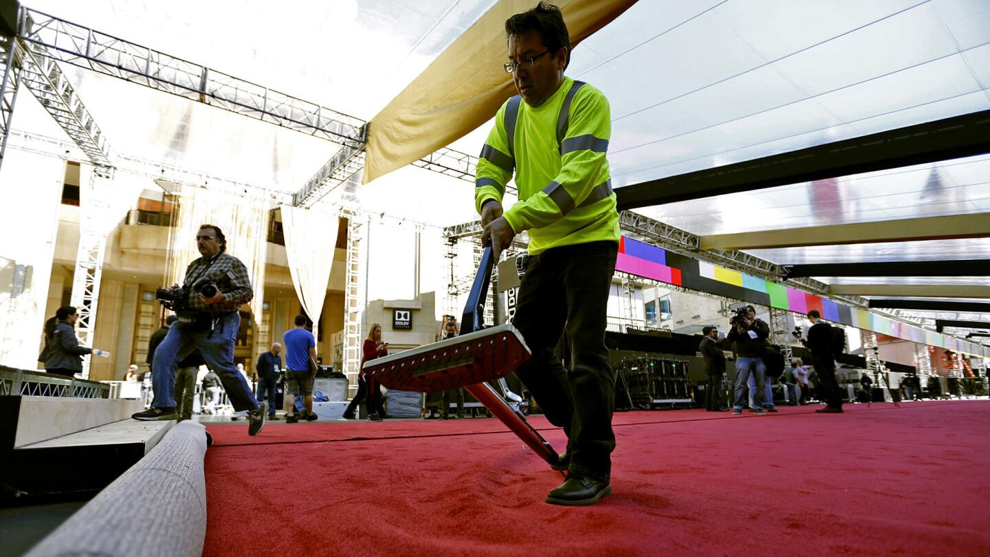 A worker unrolls the red carpet.