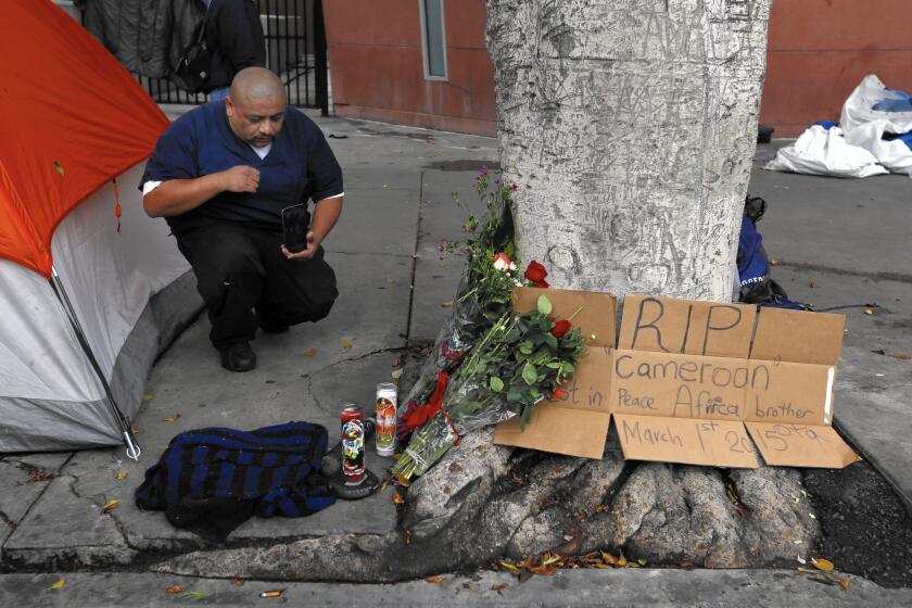 Fernando Avila kneels at the makeshift memorial near the site of Sunday's officer-involved shooting in downtown L.A.'s skid row.
