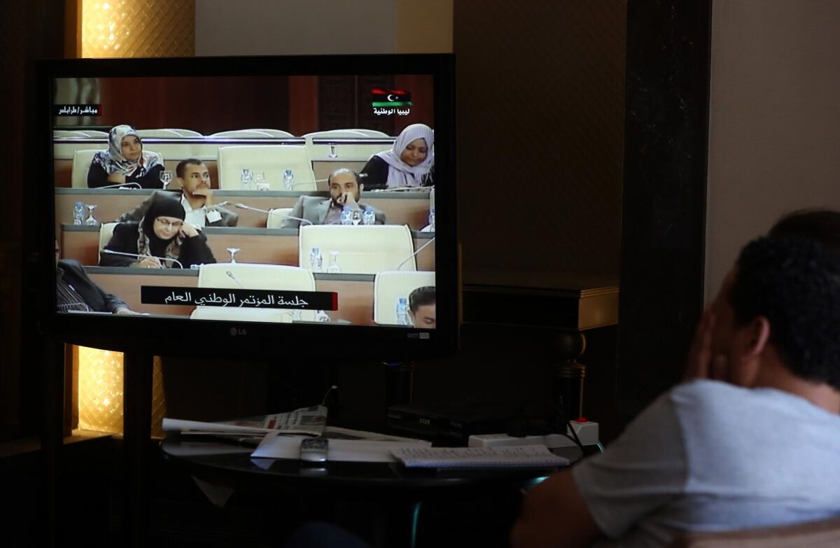 Reporters watch live video of Libya's parliament meeting to decide between two candidates for the post of prime minister.