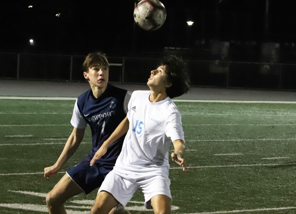 Corona del Mar's Logan Walsh (15) heads the ball with Newport Harbor's Landon Baker in pursuit on Wednesday.