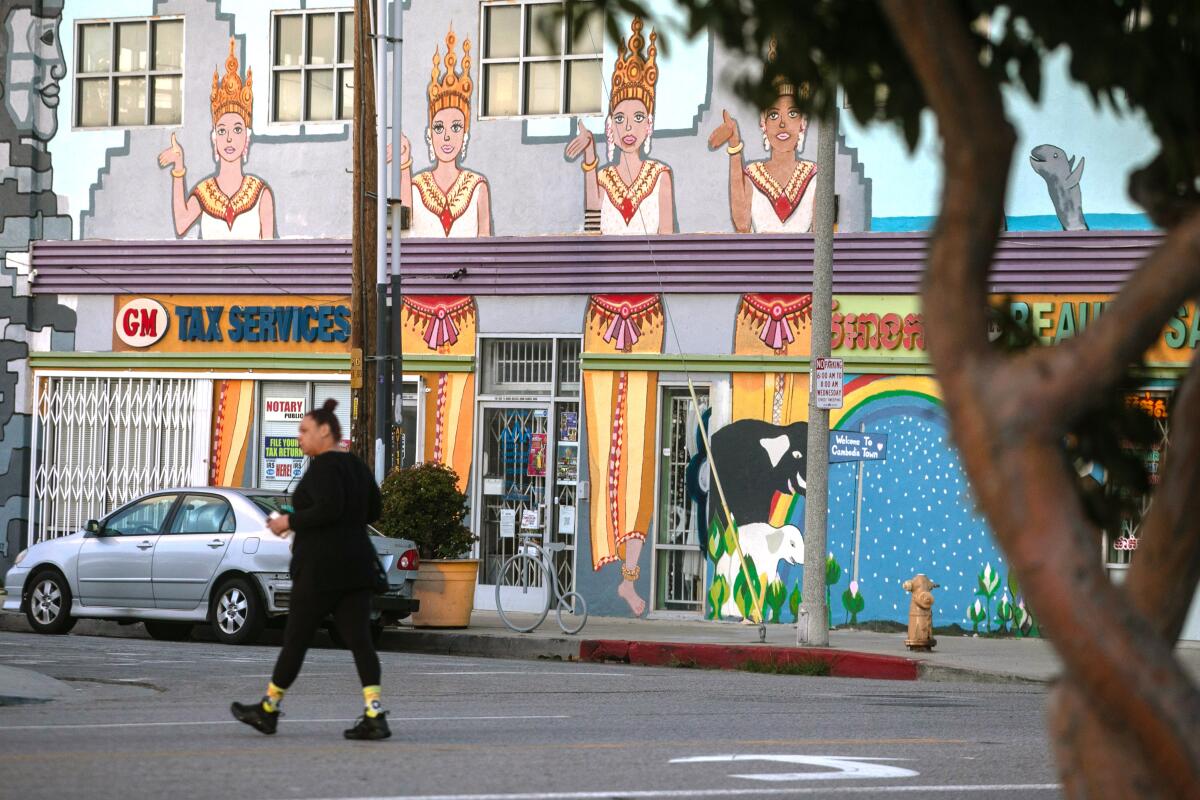 A pedestrian walks pass a mural in the Cambodia Town area of Long Beach on March 29.