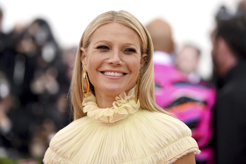Paltrow smiles at the camera on a red carpet in a tightly framed shot that shows only the ruffled neckline of her dress