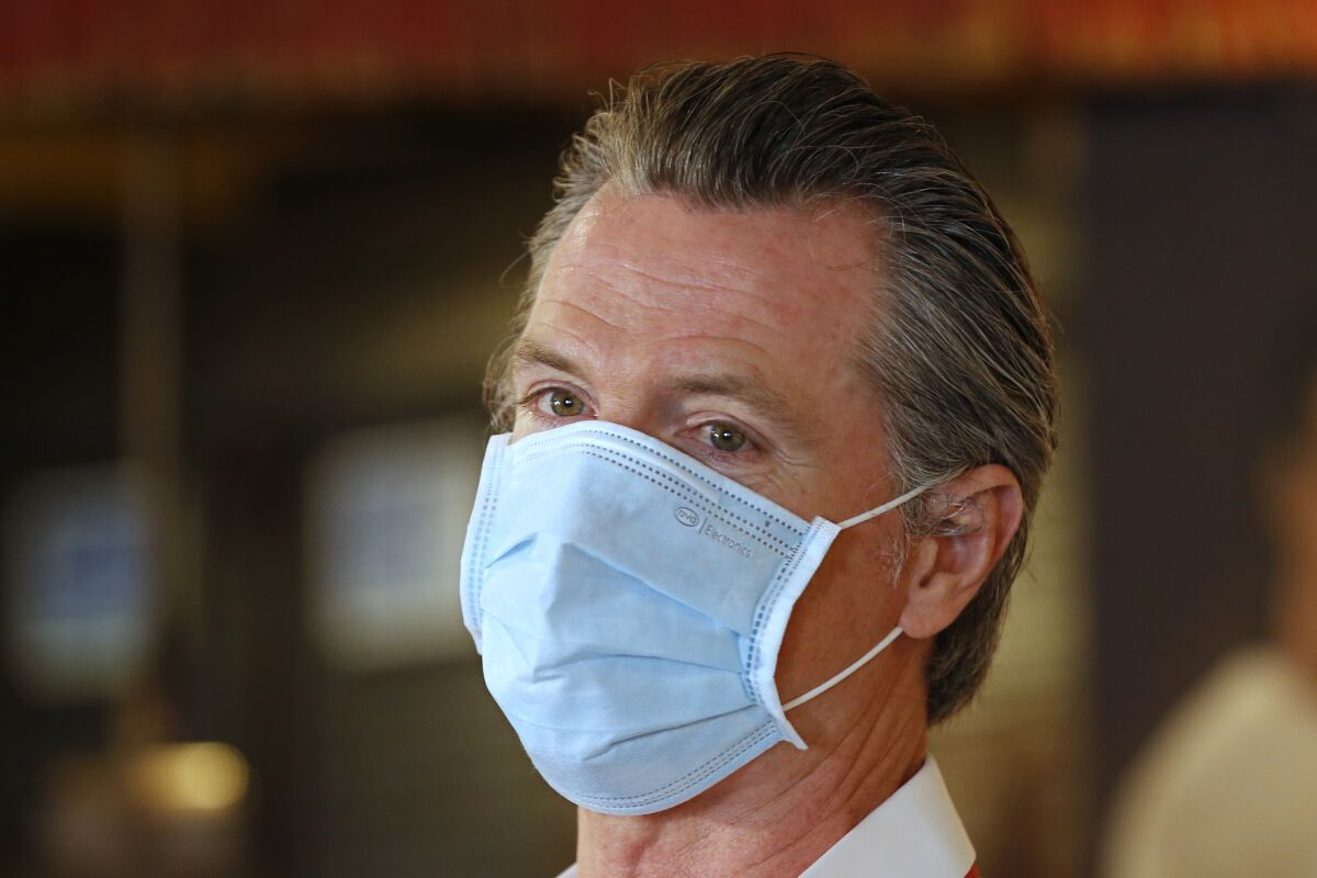 California Gov. Gavin Newsom, wears a face mask as he answers a reporter's question.
