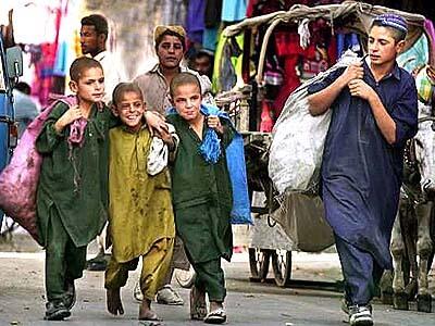 Abdul Hakim, (R),15 keeps an eye on his playful brothers on a busy market street in Quetta, Pakistan.