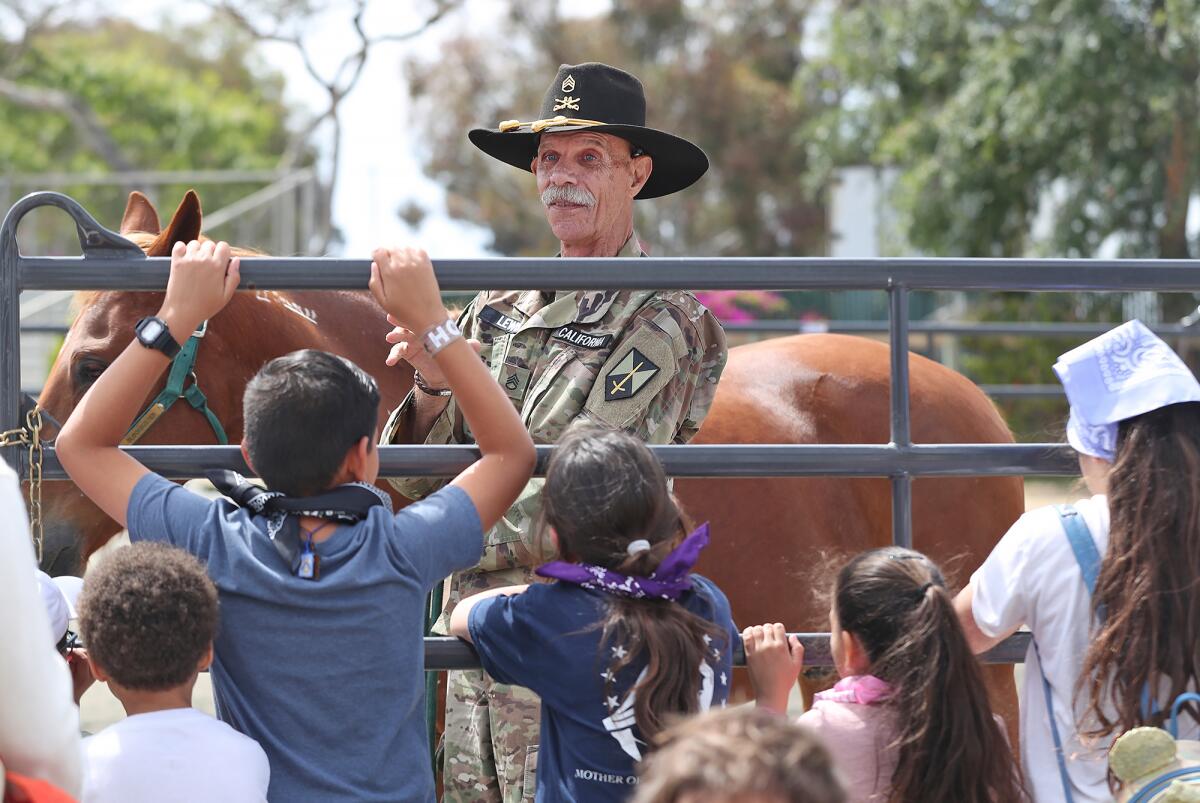 Kids listen to Sgt. Ray Lewis, of the California State Guard's 26th Calvary Detachent, at the O.C. fairgrounds on Wednesday.