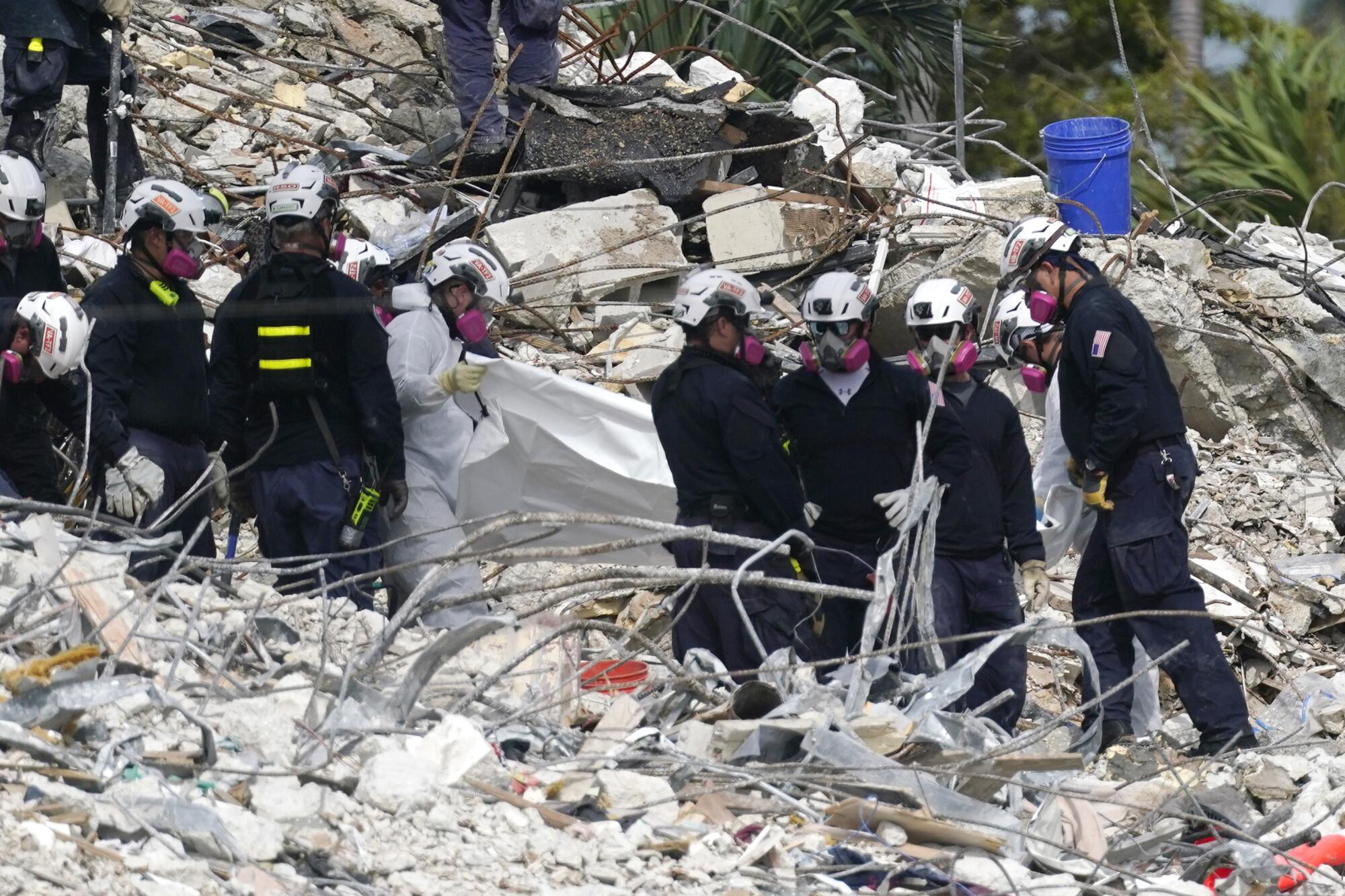 Rescue workers use a tarp for recovered remains at the site of the collapsed Champlain Towers South condo building.