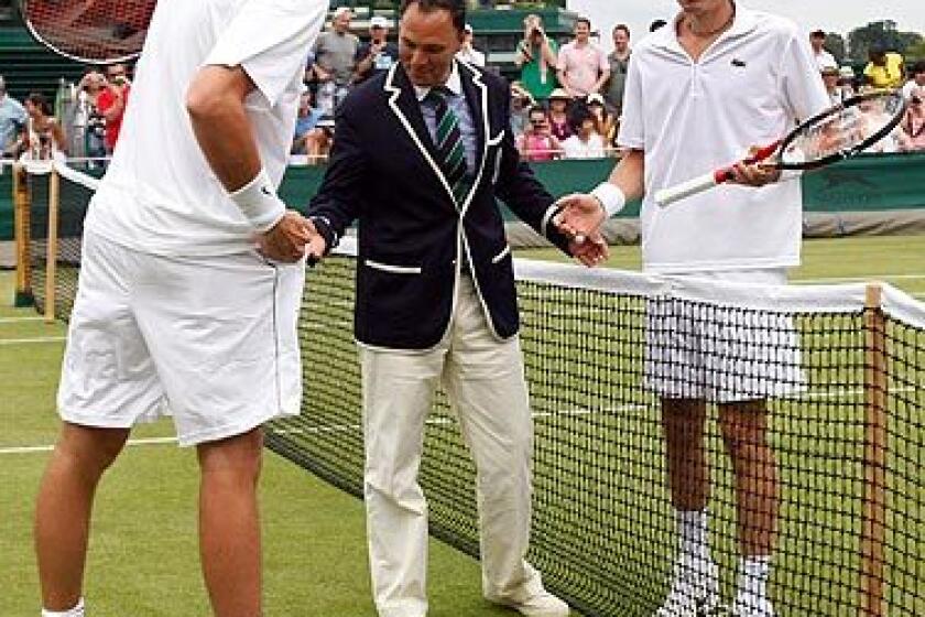 U.S. player John Isner, left, and Nicolas Mahut of France, right, talk with chair umpire Mohamed Lahyani before resuming their their epic men's singles match at the All England Lawn Tennis Championships at Wimbledon on Thursday. The match began Tuesday, was suspended because of darkness twice and was resumed with the scores tied at 59 all in the fifth set.