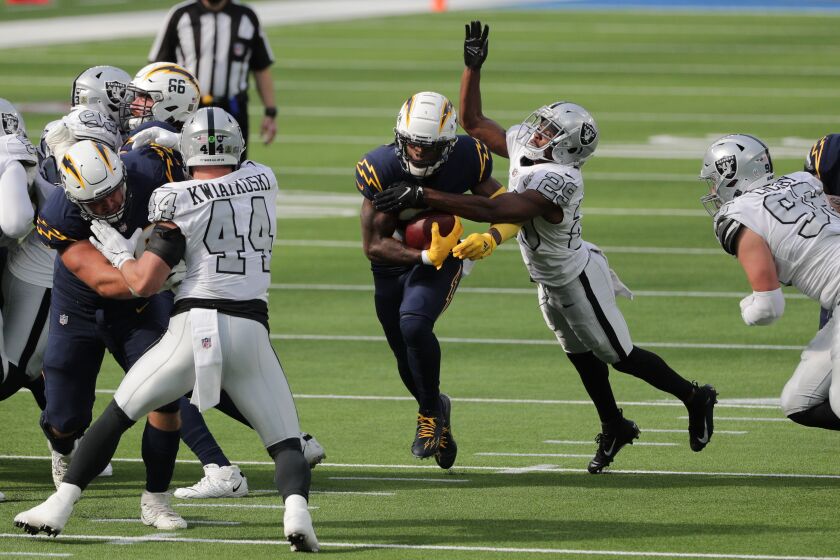 INGLEWOOD, CA - NOVEMBER 8, 2020: Chargers Kalen Ballage (31) finds a gap in the raider defense as Las Vegas Raiders free safety Lamarcus Joyner (29) tries to strip the ball in the first half on November 8, 2020 at SoFi Stadium in Inglewood, CA.(Gina Ferazzi / Los Angeles Times)